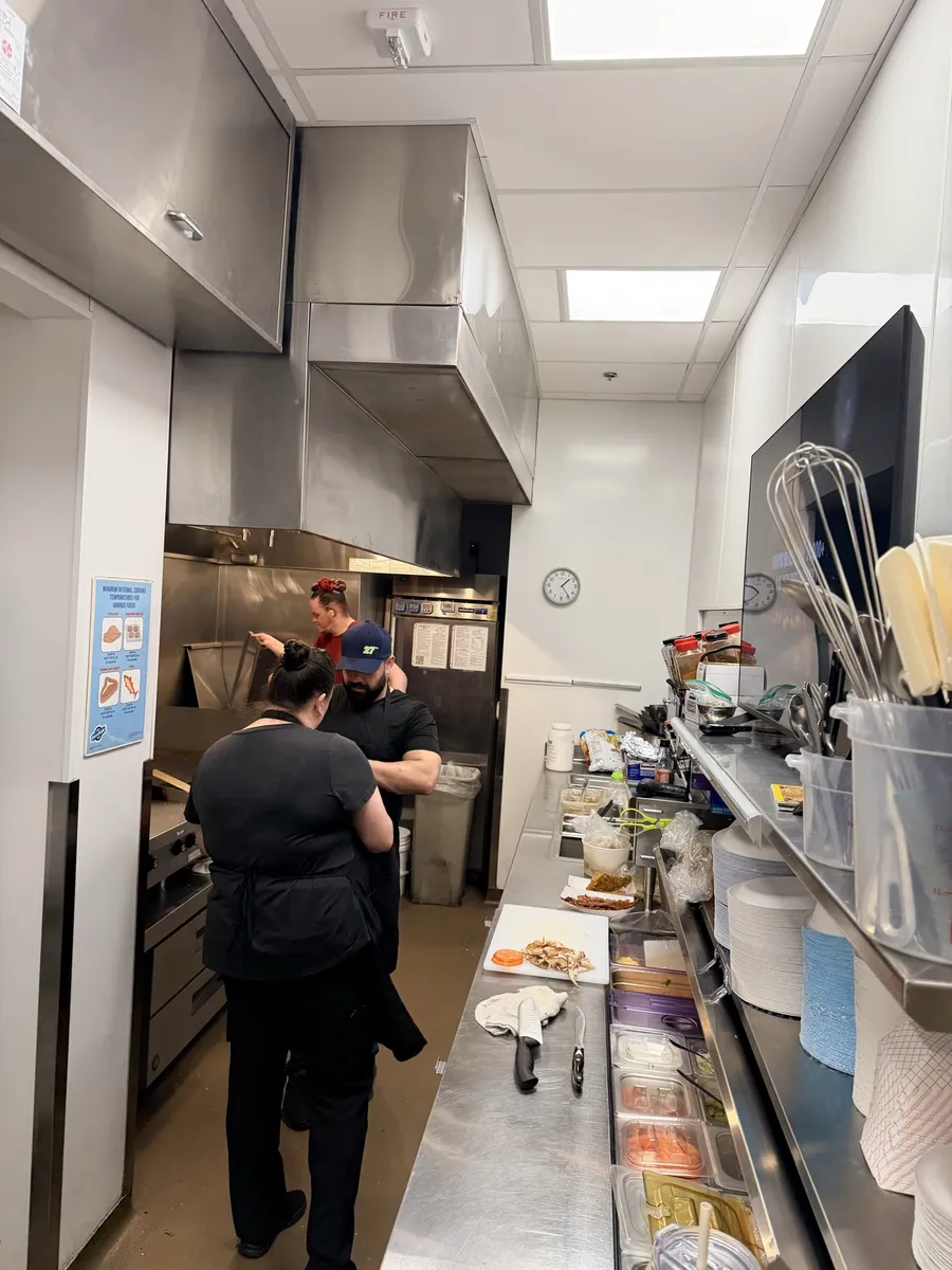 Two cooks at work at the flat top and prep line in the cafe kitchen